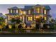 Elegant home featuring landscaped grounds, a welcoming entryway, and beautifully illuminated windows in the evening at 332 Bayley Rd, Daniel Island, SC 29492
