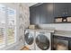 Well-appointed laundry room with modern washer and dryer, stylish cabinets, and elegant wallpaper at 332 Bayley Rd, Daniel Island, SC 29492