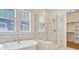 Spa-like bathroom featuring a soaking tub and glass-enclosed shower, next to bright windows at 503 Ivy Green Ln, Summerville, SC 29486