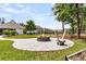 Beautiful stone fire pit with Adirondack chairs in a backyard with mature landscaping and green lawn at 512 Pontoon Rd, Huger, SC 29450