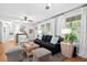 Comfortable living room with hardwood floors, ceiling fan, a black sofa with patterned pillows, and lots of natural light at 520 Yale Dr, Charleston, SC 29412