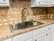 Close-up of a kitchen sink with neutral tile counters, stainless steel sink and faucet and white cabinetry at 7914 Dutch Ct, North Charleston, SC 29420
