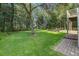 Manicured backyard with lush lawn, mature trees, and a stone patio with seating area at 8657 Refuge Point Circle Cir, Charleston, SC 29420