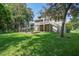 Expansive backyard featuring a stone patio, manicured lawn, mature trees and a large home at 8657 Refuge Point Circle Cir, Charleston, SC 29420