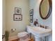 Charming powder room with pedestal sink, decorative mirror, and warm color palette at 8657 Refuge Point Circle Cir, Charleston, SC 29420