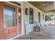 Inviting front porch with wood flooring, rustic lanterns, rocking chair, and wooden front door at 8657 Refuge Point Circle Cir, Charleston, SC 29420