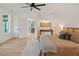 Bright main bedroom featuring a ceiling fan, hardwood floors, view into the kitchen, and neutral decor at 1014 E Erie Ave, Folly Beach, SC 29439