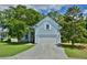 Charming light blue home featuring a well-manicured lawn, mature trees, and a two-car garage at 106 Trimley Ct, Goose Creek, SC 29445