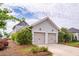 Two-car garage with lush landscaping and a well-maintained exterior, complemented by a clear blue sky at 107 Clear Bend Ln, Summerville, SC 29486