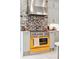 Close-up of the gourmet kitchen with a stainless steel range hood and a striking yellow oven at 11 Franklin St, Charleston, SC 29401