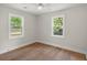 Empty bedroom featuring hardwood floors, two windows, ceiling fan and fresh white paint at 1109 Hillside Dr, Charleston, SC 29407