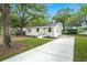 Low angle view of a white brick house with a long driveway and mature landscaping in the front yard at 1109 Hillside Dr, Charleston, SC 29407