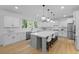 Open kitchen with quartz counters, white cabinets, stainless appliances and a large island with pendant lighting at 1411 Homecoming Blvd, Ravenel, SC 29470