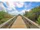 A wooden walkway stretches across marshland, leading towards a community dock on a sunny day at 1505 Fort Palmetto Cir, Mount Pleasant, SC 29466