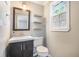 Cozy powder room with a dark vanity, floating wood shelves, and a window at 2010 Culver Ave, Charleston, SC 29407