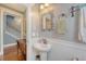 Hallway with a view into the half bathroom featuring a pedestal sink, vintage-style mirror, and beadboard at 209 Forsythia Ave, Summerville, SC 29483