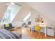 Bright attic bedroom features hardwood floors, white walls, desk, and accent chair under natural light at 21 1/2 Pitt St, Charleston, SC 29401