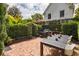 Charming brick patio with string lights, an outdoor grill, bench, dining table, and garden surroundings at 21 1/2 Pitt St, Charleston, SC 29401
