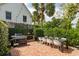 Charming brick patio with string lights, an outdoor grill, dining table, and garden surroundings at 21 1/2 Pitt St, Charleston, SC 29401