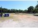 A dirt baseball field is surrounded by a chain link fence and mature trees with bright blue trash cans in the foreground at 2169 Westrivers Rd, Charleston, SC 29412