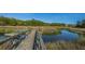 Scenic view of a wooden pier extending into a tranquil waterway surrounded by marsh grass at 225 River Oak Dr, Mount Pleasant, SC 29464