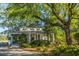 Charming home exterior featuring a covered porch, lush landscaping, and mature trees at 225 River Oak Dr, Mount Pleasant, SC 29464