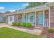 Close-up of a charming porch and entrance with blue door, brick facade, and neatly trimmed green bushes at 2534 Flamingo Dr, Charleston, SC 29414