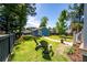 Grassy backyard with mature trees, seating, fenced perimeter, and a storage building with a concrete walkway at 2627 Rutherford Way, Charleston, SC 29414