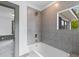 Bathroom with gray tiles, large window, tub, and brass shower fixtures at 285 Roosevelt Dr, Saint Stephen, SC 29479