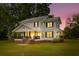 Charming two-story home with a covered porch, large yard, and warm lighting at twilight at 285 Roosevelt Dr, Saint Stephen, SC 29479