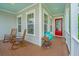 Relaxing front porch with rocking chairs, vibrant flower pot, and a charming red door entrance at 2962 Clearwater Dr, Mount Pleasant, SC 29466