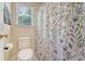 Toilet and shower in a naturally lit bathroom with floral shower curtain and a window at 322 Clubview Rd, Summerville, SC 29485