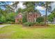 Beautiful red brick home with lush landscaping, mature trees, and a well-maintained front lawn at 322 Clubview Rd, Summerville, SC 29485