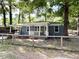 Quaint exterior view showcasing the charming blue brick home with a fenced yard, mature trees, and inviting front porch at 354 Deloach Ave, Walterboro, SC 29488
