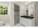 Bright bathroom with black countertop, white cabinets, a glass shower, and a toilet under the window at 3756 Colonel Vanderhorst Circle, Mount Pleasant, SC 29466
