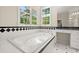 Bathroom features a soaking tub under a window with black and white tiled accents at 3756 Colonel Vanderhorst Circle, Mount Pleasant, SC 29466