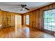Hardwood floors, wood paneling, and three windows illuminate this living room space with ceiling fan at 4327 Bream Rd, North Charleston, SC 29418