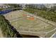 Aerial view of a baseball field with well-maintained grass, clay infields, and sports lighting, surrounded by community lakes and trees at 555 Dunswell Dr, Summerville, SC 29486