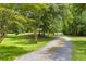 Gravel driveway leading through a tree-lined landscape, offering a sense of privacy and natural beauty at 6035 Bay Pond Rd, Ravenel, SC 29470