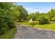 Gravel driveway and lush greenery, enhanced by the American flag, exuding charm and character at 6035 Bay Pond Rd, Ravenel, SC 29470