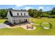 Aerial view of a home featuring a fire pit, putting green, covered porch, two-car garage, and manicured lawn at 795 Shagule Rd, Edisto Island, SC 29438