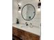 Modern bathroom boasts a wood vanity, round mirror, and stylish wall sconces at 795 Shagule Rd, Edisto Island, SC 29438