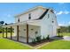 Modern two-story white home featuring a garage, covered patio, and well-maintained landscaping, perfect for outdoor living at 795 Shagule Rd, Edisto Island, SC 29438