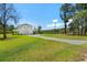 Spacious white home featuring a well-manicured lawn, stone driveway, and covered porch, perfect for a tranquil country living at 795 Shagule Rd, Edisto Island, SC 29438