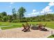 Outdoor area with stone fire pit and Adirondack chairs on a patio, with a putting green nearby and lush greenery at 795 Shagule Rd, Edisto Island, SC 29438