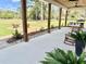 Covered patio with wooden beams, a comfortable swing, rocking chairs, and an outdoor fireplace at 795 Shagule Rd, Edisto Island, SC 29438