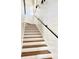 Bright staircase with white risers and stained wood treads and a black railing contrasts with white plank walls at 795 Shagule Rd, Edisto Island, SC 29438