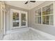 Inviting covered patio with neutral siding, ceiling fan, and tile floor, accessible through elegant glass doors at 828 Williamsburg Ln, Charleston, SC 29414