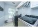 Well-lit laundry room with modern washer and dryer units, storage cabinets, and a view through the window at 9636 Pebble Creek Blvd, Summerville, SC 29485