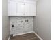 Practical laundry room with upper white cabinets and a marble-tiled wall ready for appliances and organized living at 102 Six Point Ct, Goose Creek, SC 29445